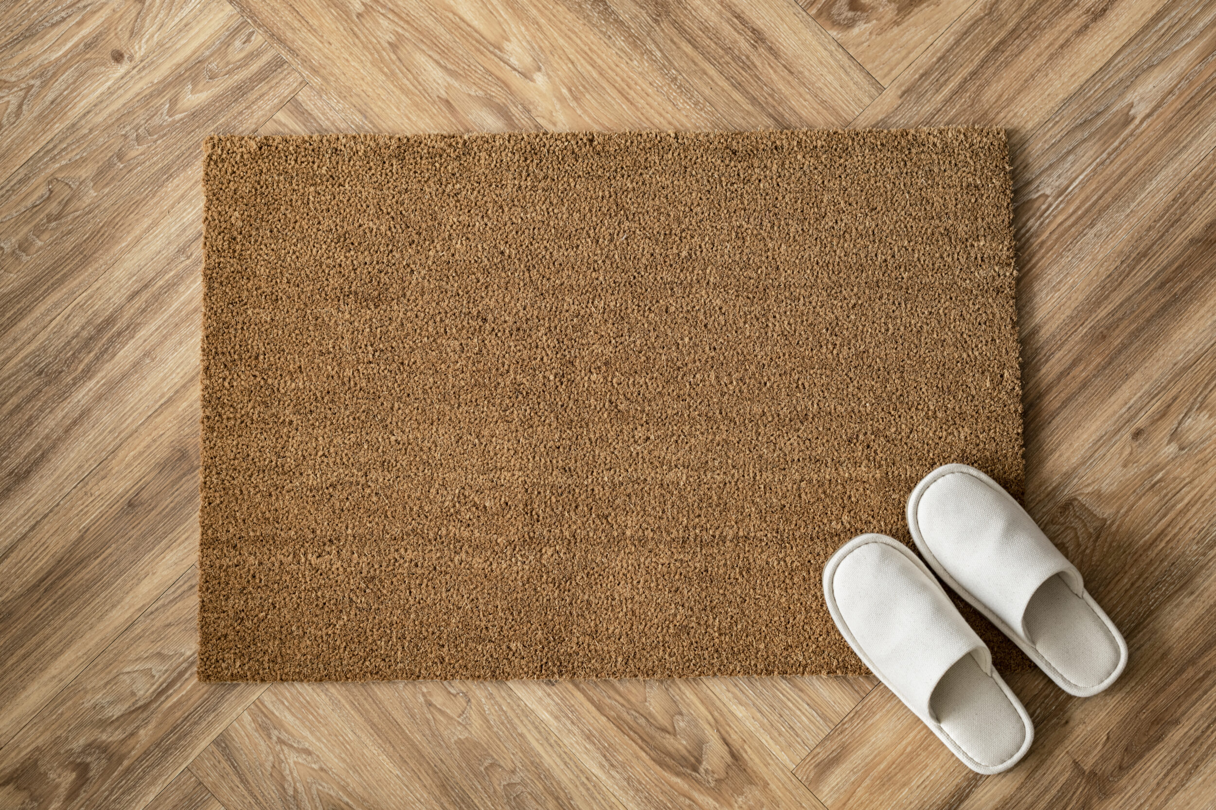 zapatillas de estar por casa blancas encima de un felpudo marrón claro