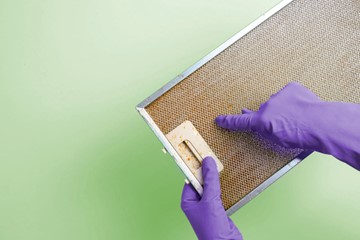 Manos Con Guantes De Color Morado Sosteniendo Un Filtro De Campana Extractora Lleno De Grasa