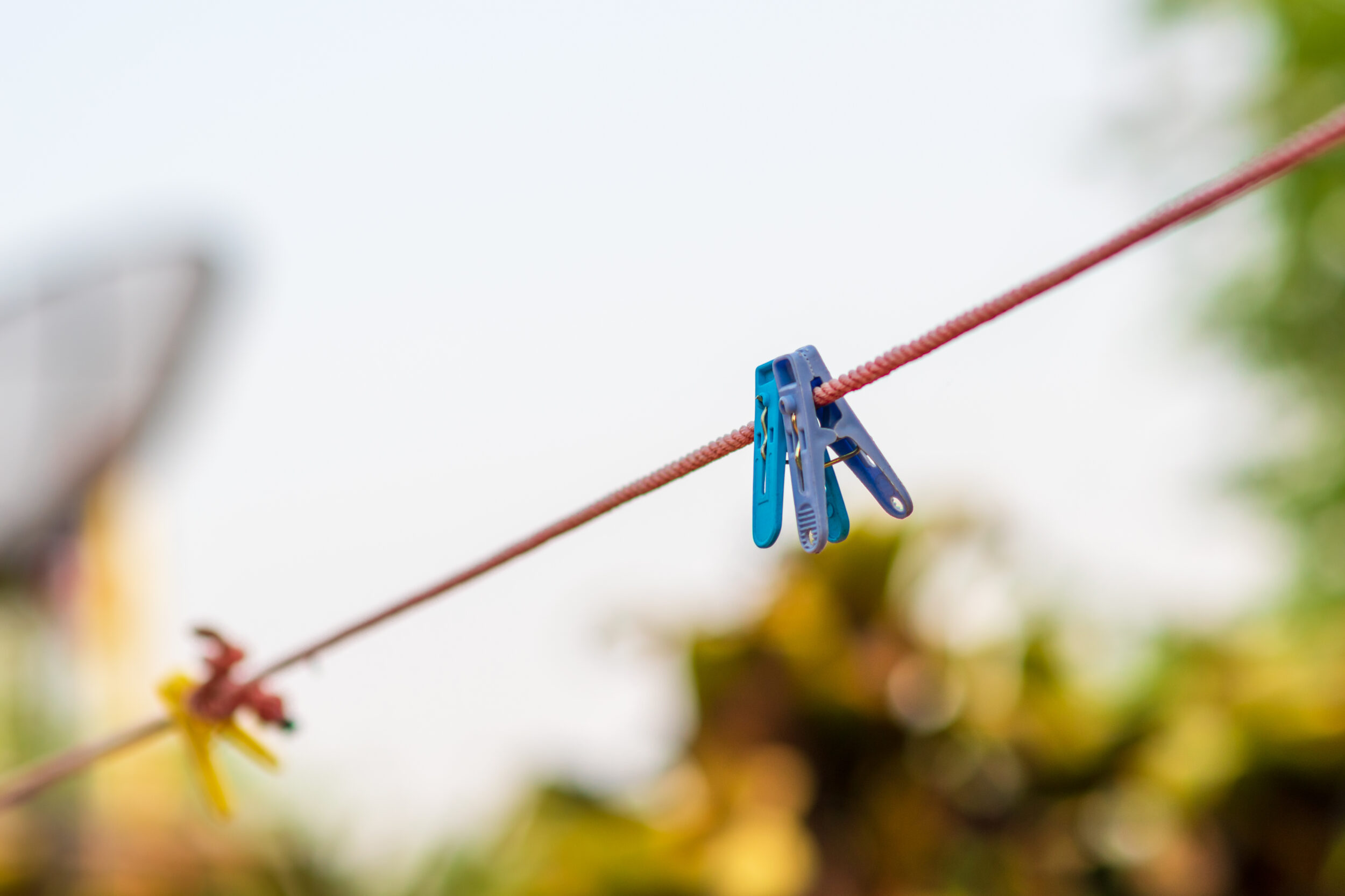 Primer plano de pinzas de ropa en una cuerda contra el cielo