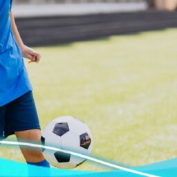 Niño de piel morena y vestido con ropa de color azul jugando a futbol