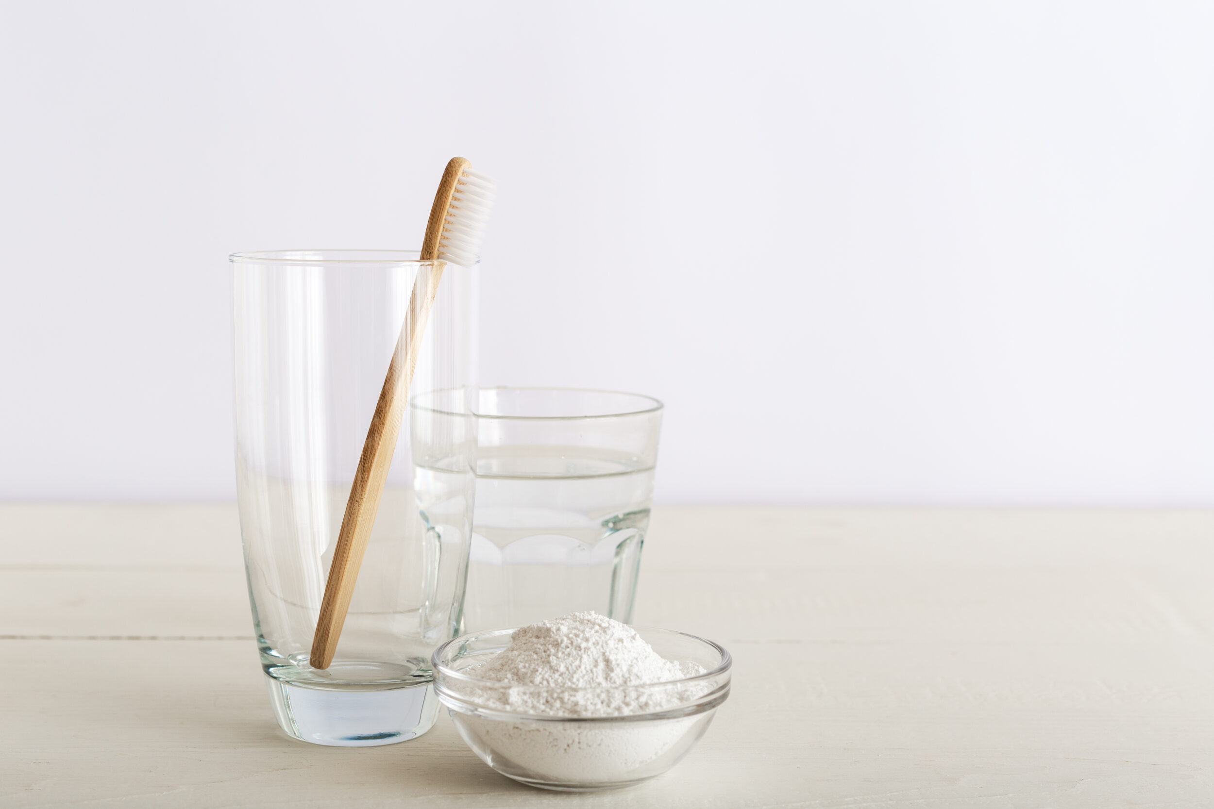 vaso con agua, bol con bicarbonato de sodio, y un cepillo de dientes